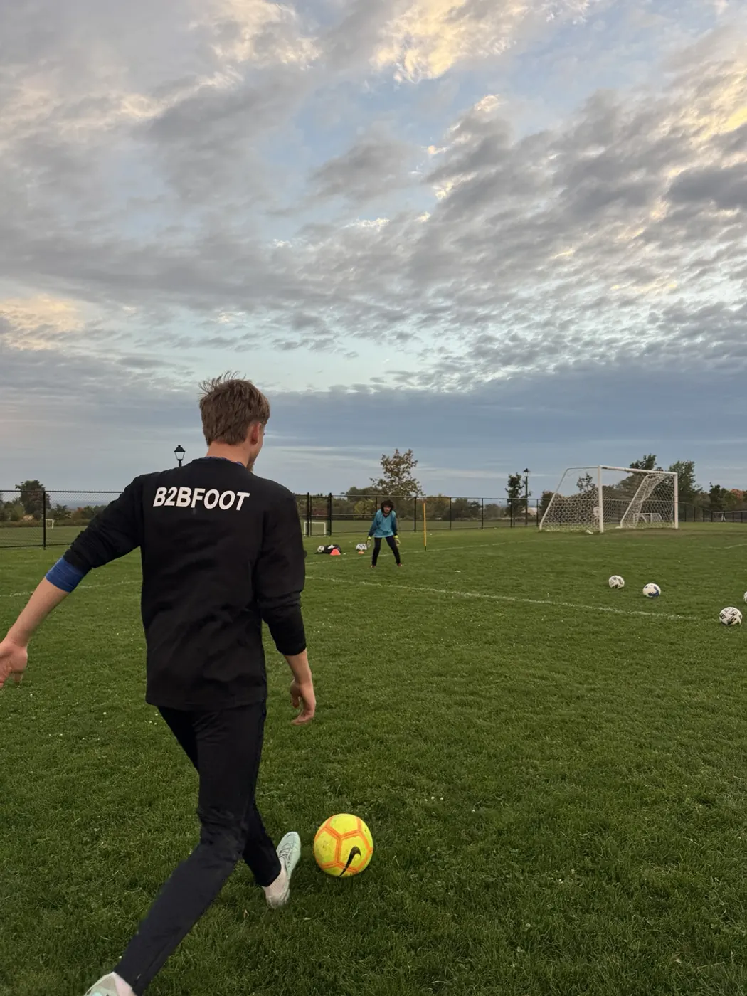 B2B coach working with a goalkeeper on the pitch at sunset